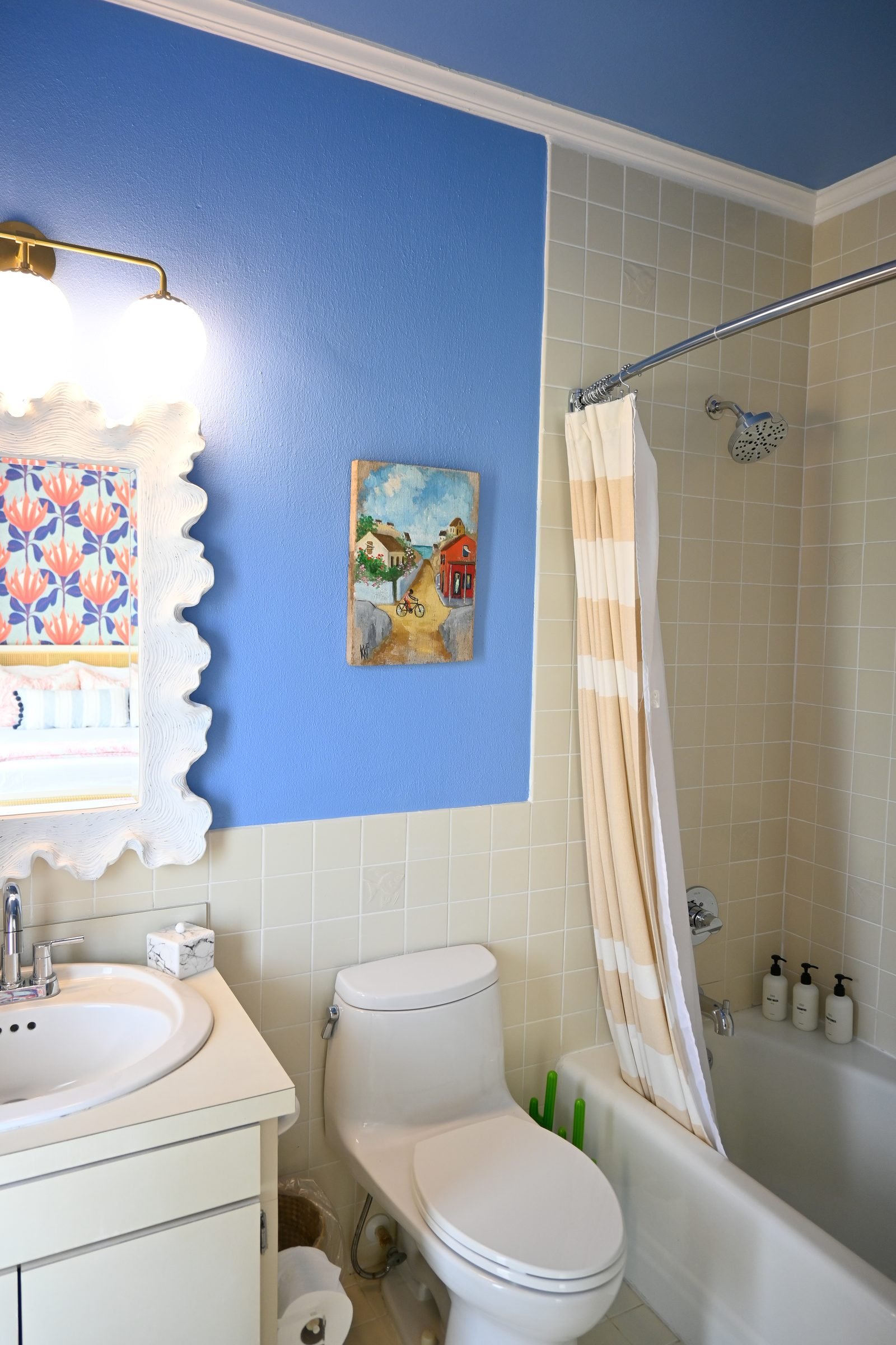 Flamingo Sisters ensuite — blue walls with beige striped shower curtain and colorful artwork
