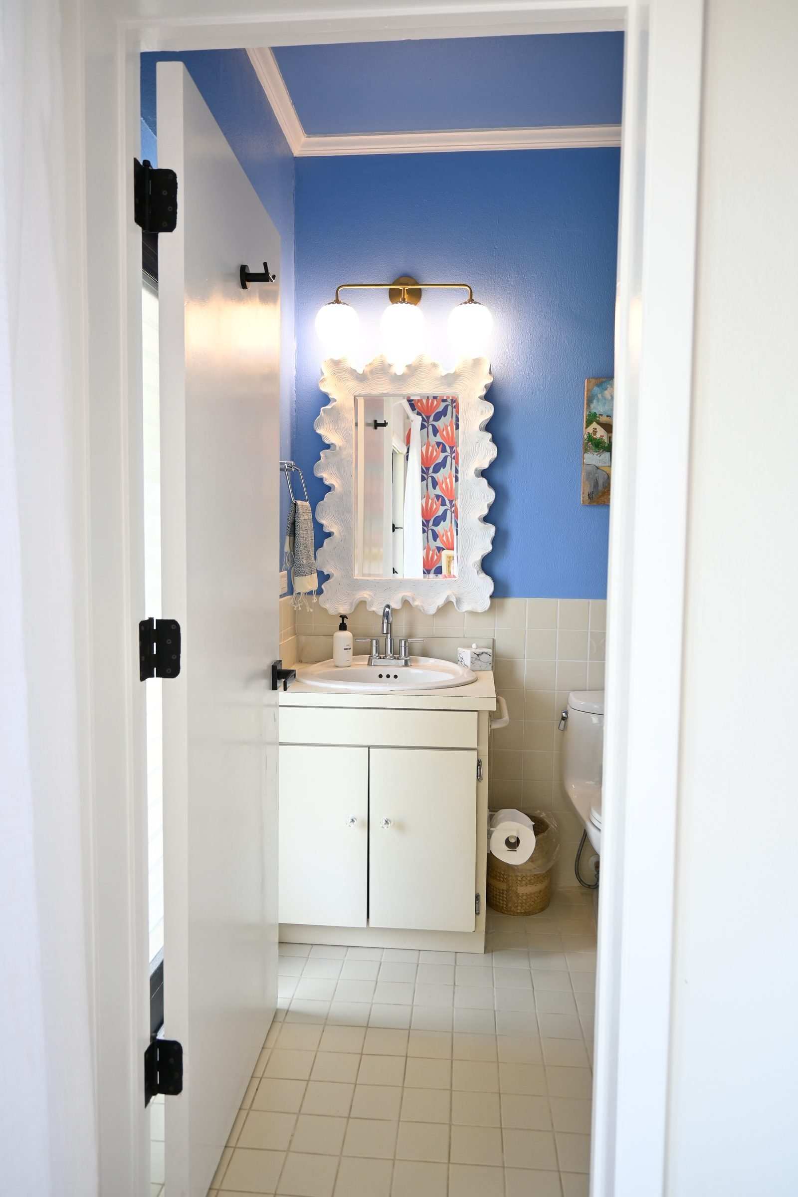 Flamingo Sisters ensuite — white vanity with scalloped mirror and blue walls