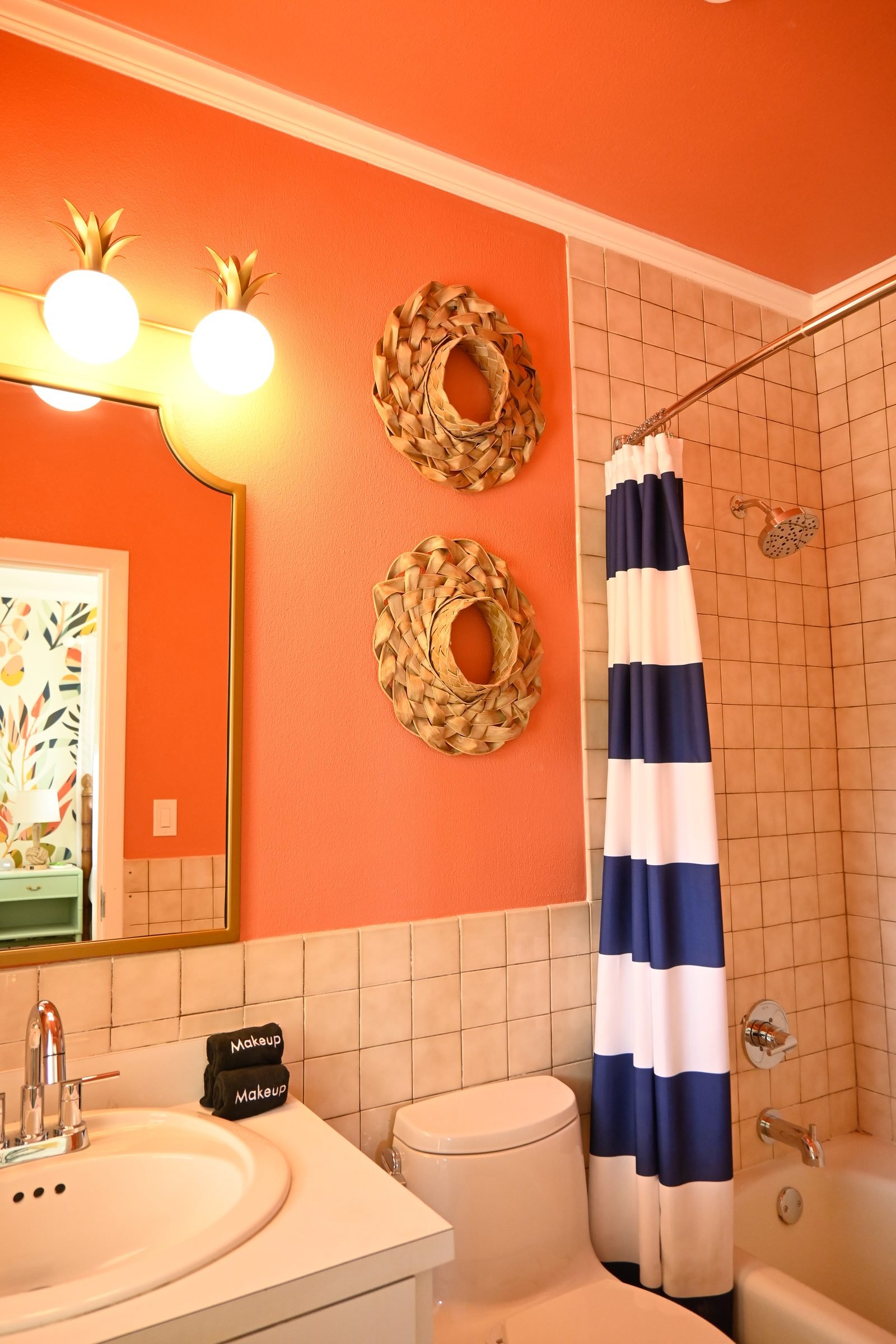 Pineapple Suite ensuite — coral walls with navy-striped shower curtain